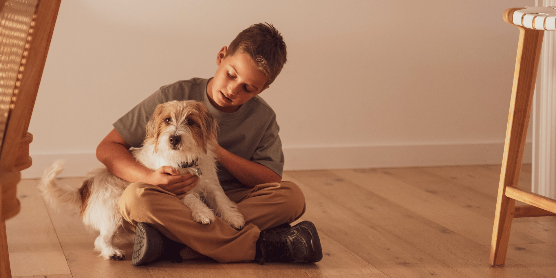 Boy sitting on a timber floor holding a small dog