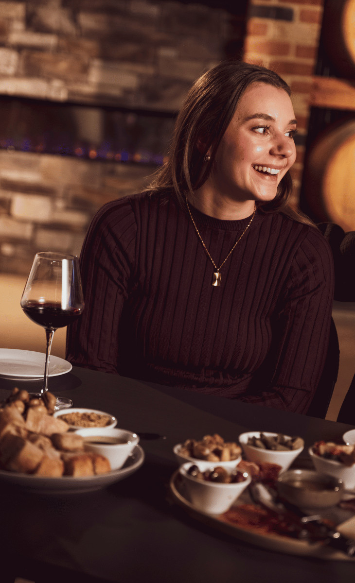 Woman with a glass of wine and share plates at a restaurant